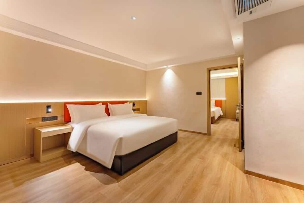 A modern hotel room with a large bed, a bedside table, and a nightstand.