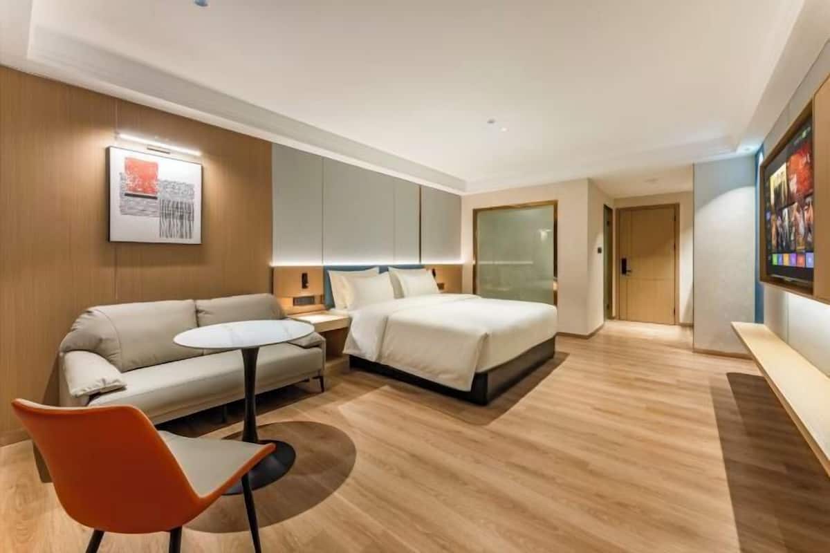 A modern hotel room with a bed, a sofa, a small table, and a chair.