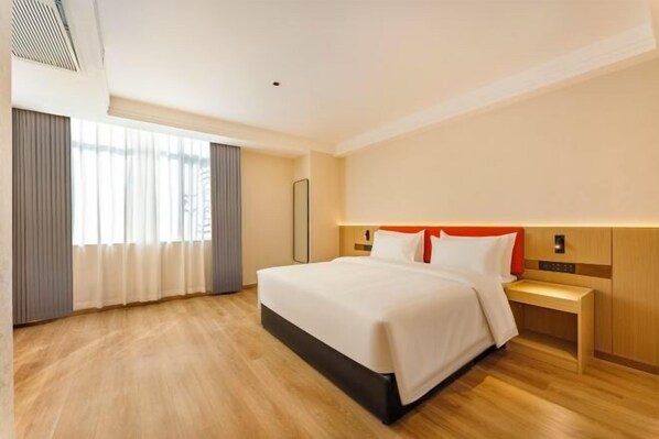 A hotel room with a large bed, a bedside table, a nightstand, and a window with curtains.