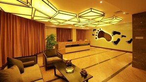 A hotel lobby with a reception desk, seating area, and a wall with a large footprint design. - Wind bell Hotel (Foshan Guicheng Metro Station) (Foshan)