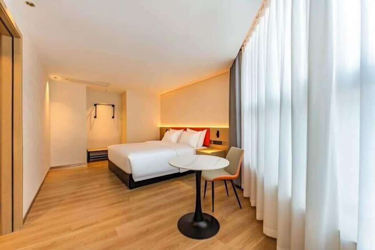 A hotel room with a bed, a small table, a chair, and a nightstand.