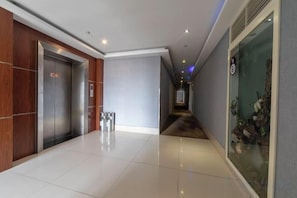 A hallway with an elevator, a glass fish tank, and a polished floor. - A·K·S Fashion Hotel (Wenzhou)