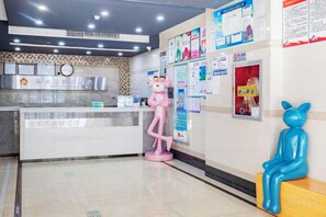 A reception area with a counter, a clock, and informational posters on the wall. - A·K·S Fashion Hotel (Wenzhou)