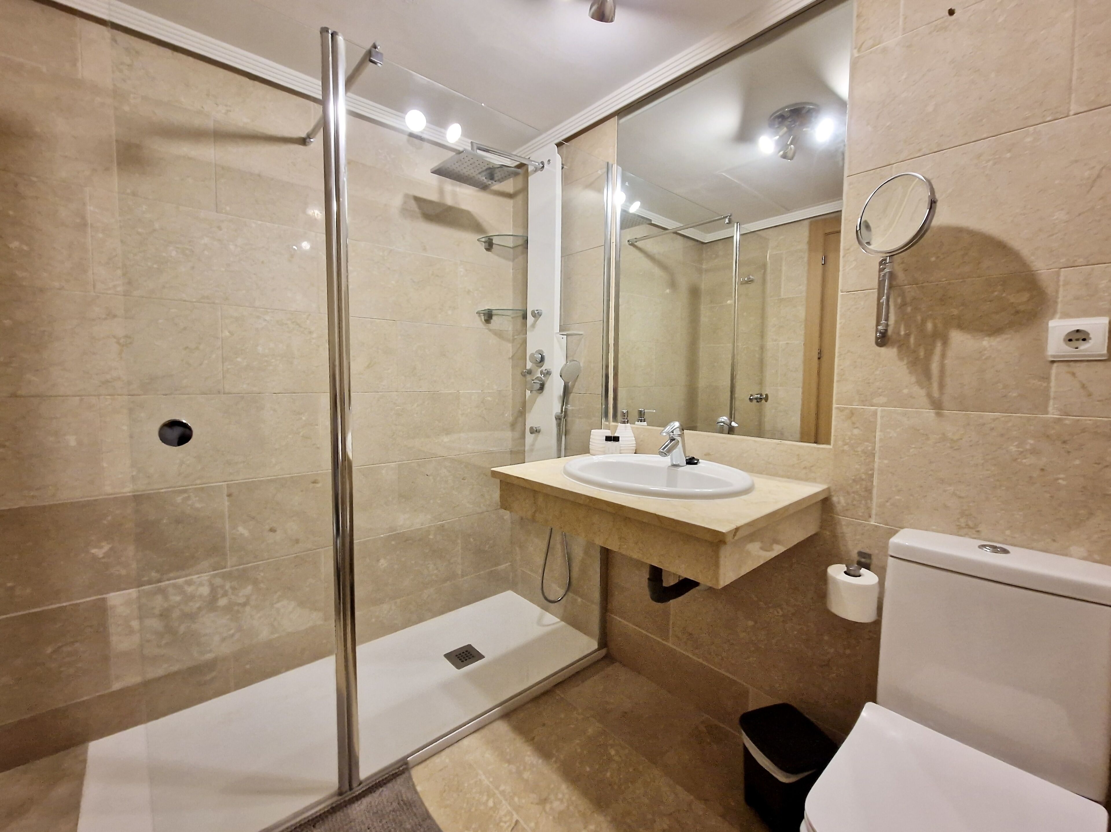 A modern bathroom with a glass-enclosed shower, a sink with a mirror, and a toilet.