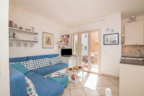 Una sala de estar con un sofá azul, un televisor y una mesita con una bandeja de comida.