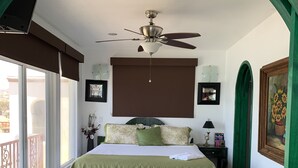 A bedroom with a bed, a ceiling fan, a window with a view, and a door leading to another room. - Spectacular oceanview penthouse - rooftop terrace, bbq, pool, jacuzzi & beach (Primo Tapia)