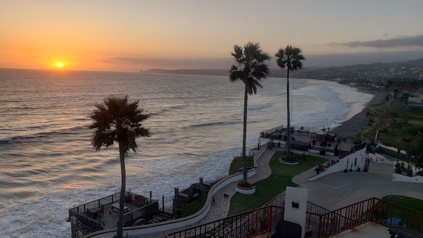 A coastal view with a sunset, palm trees, and a patio area with outdoor seating. - Spectacular oceanview penthouse - rooftop terrace, bbq, pool, jacuzzi & beach (Primo Tapia)