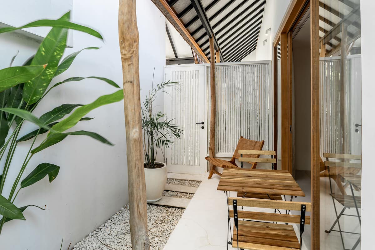 A covered outdoor seating area with wooden benches and a potted plant.