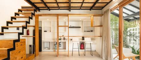 A modern interior with a wooden staircase, open shelving, and a glass door leading to an outdoor area.