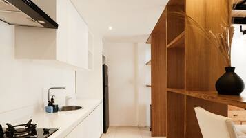 A modern kitchen with white cabinetry, a black stove, and a wooden accent wall.