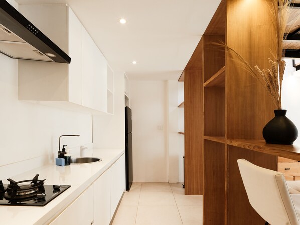 Una cocina moderna con armarios blancos, una estufa negra y una pared de acento de madera.