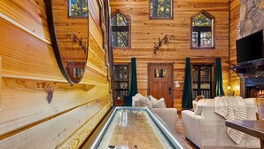 A cozy log cabin interior with a central glass-top table, wooden walls, and a fireplace.