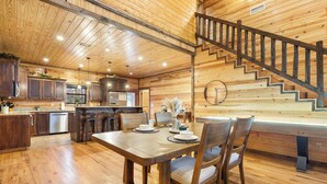 A wooden interior with a dining area, kitchen, and staircase.