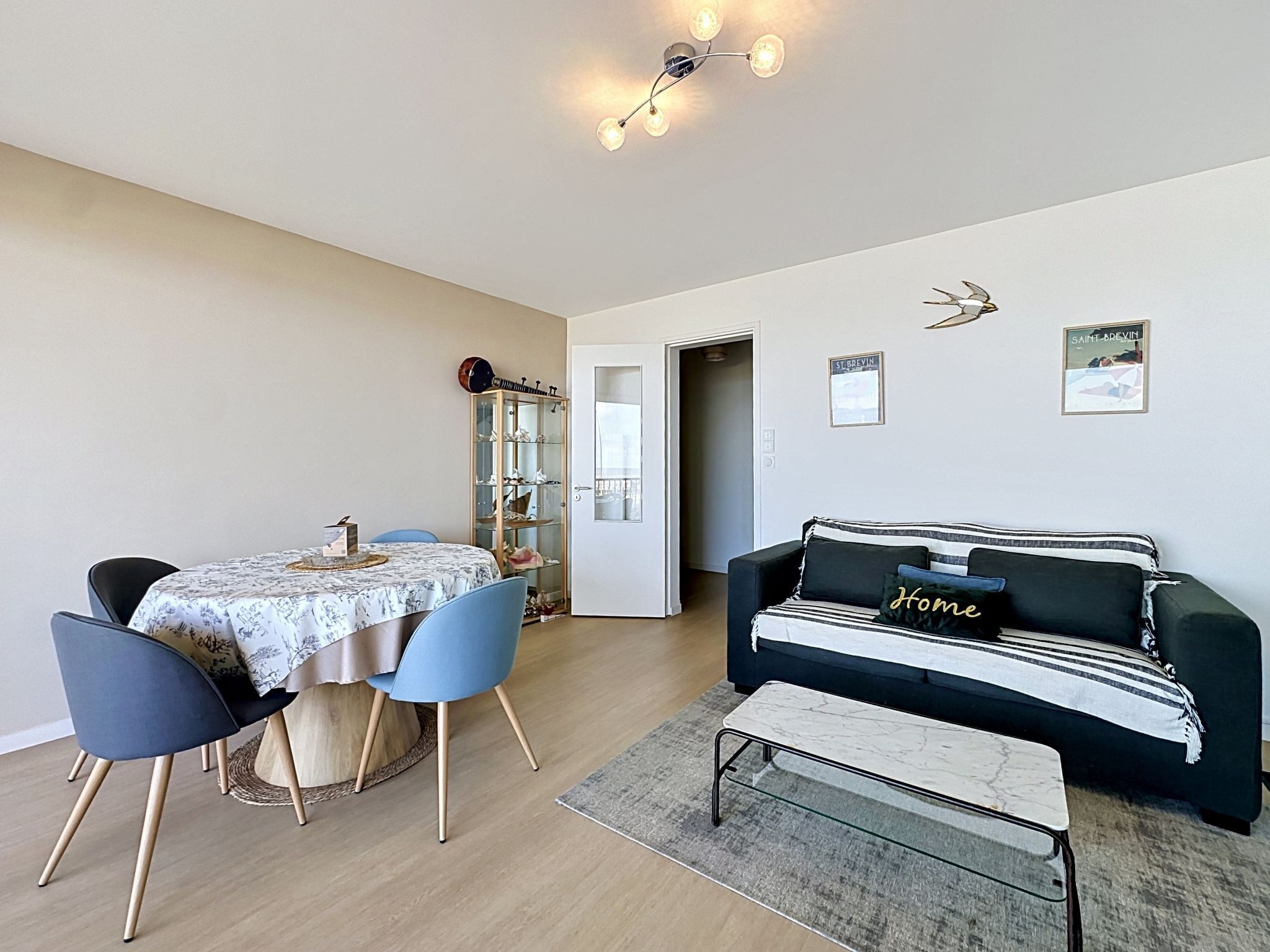 Un espace repas comprenant une table, des chaises, un meuble vitré, un canapé, un banc et un luminaire suspendu au plafond.