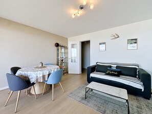 Un espace repas comprenant une table, des chaises, un meuble vitré, un canapé, un banc et un luminaire suspendu au plafond.