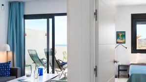 Una habitación de hotel con balcón, cama, escritorio y una silla.