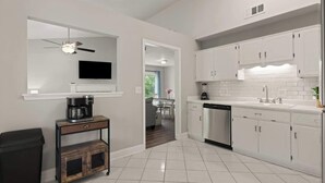 A modern kitchen with white cabinets, a dishwasher, and a coffee maker on a small table. - Tipsy Turtle - New Listing (Brunswick)