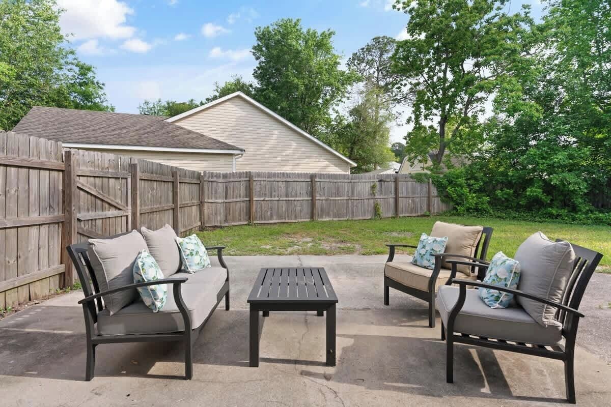 An outdoor patio with two sofas and a table, surrounded by a wooden fence.