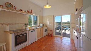 Una cocina equipada con lavavajillas, horno y lavadora. Se aprecia una ventana con vistas al exterior.