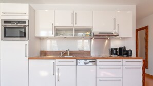A modern kitchen with white cabinetry, a built-in oven, a microwave, and a coffee maker. - Boulevard Louis Blanc by Interhome (Saint-Tropez)