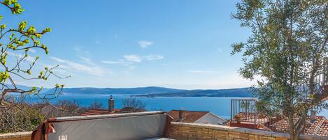 A hot tub with a clear view of the sea and mountains in the background.