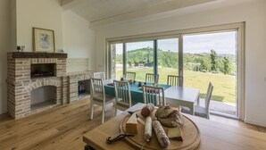 Un comedor con una mesa dispuesta para dos, una chimenea y vistas a un paisaje verde.