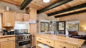 Eine moderne Küche mit Holzausbau, Edelstahlgeräten und einer großen Kücheninsel mit Stauraum.