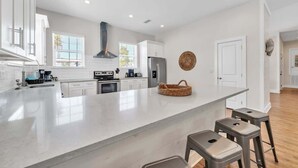 Une cuisine moderne avec des meubles blancs, un grand îlot central et des tabourets de bar.