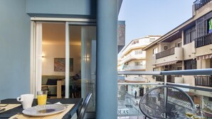 Ein Balkon mit einem Tisch für zwei Personen, einem Stuhl und einem Essbereich, der im Inneren sichtbar ist.