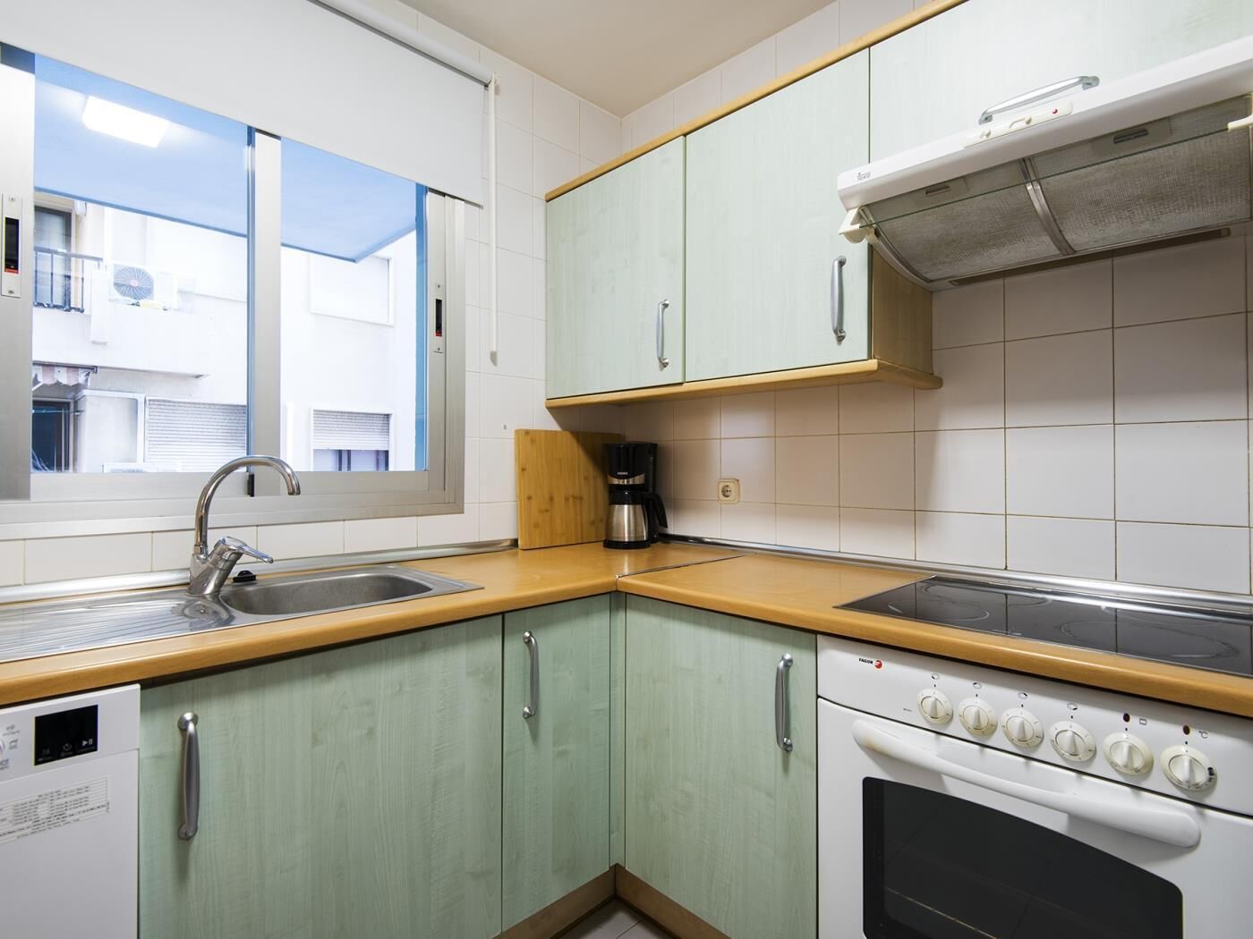 A compact kitchen with a window, a built-in oven, and a coffee maker.