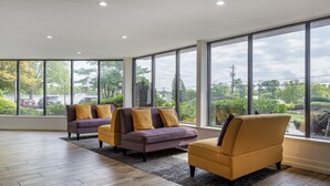 Una habitación amplia con ventanas grandes, un sofá morado y un sillón amarillo.