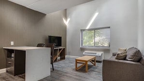 Una sala de estar moderna con un televisor de pantalla plana, un sofá, una mesa de centro y un escritorio con una silla.