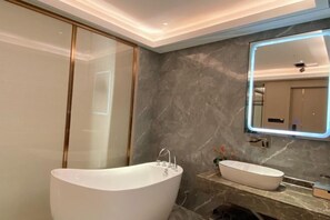 Un bany modern amb una banyera autònoma, un lavabo sobretaulella i un mirall amb il·luminació integrada.