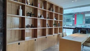 A reception area with a wooden reception desk and a large shelving unit with various items.