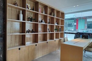 Zona de recepción con un mostrador de madera y un estante grande con diversos objetos.