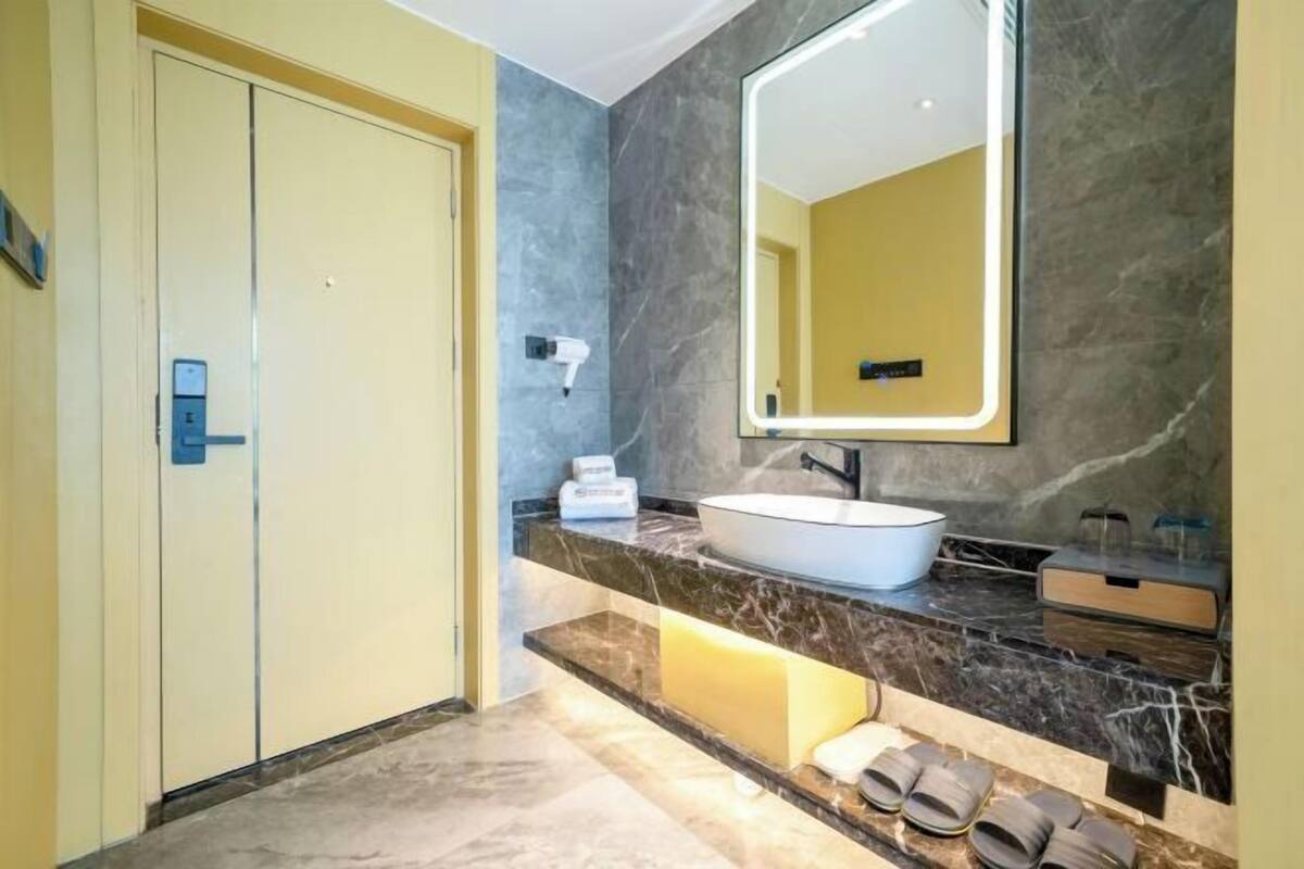 Een moderne badkamer met een marmeren aanrechtblad, een grote spiegel, een wastafel en een handdoekhouder.