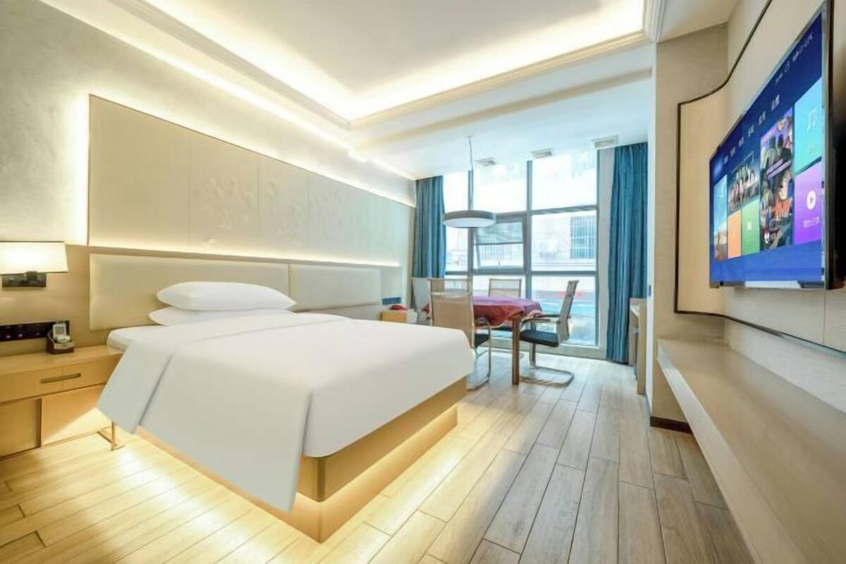 Een moderne hotelkamer met een groot bed, nachtkastjes, een bureau en een televisie.