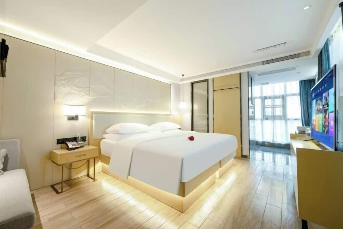 Een moderne hotelkamer met een groot bed, nachtkastje en een televisie.