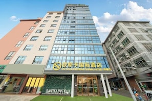 A hotel with a modern glass facade, multiple floors, and a prominent signage for the hotel. - Ou Si Ka lnternational Hotel (Danzhou)
