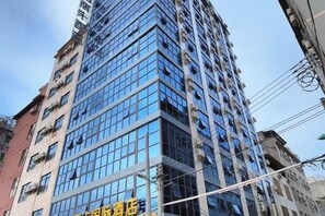 Un edificio alto con varios pisos, amplias ventanas y cielo despejado.