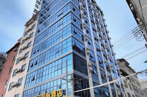 Un edificio alto con varios pisos, amplias ventanas y cielo despejado.