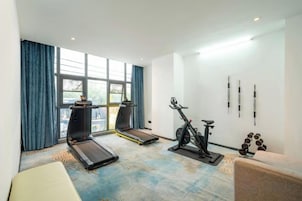 Habitación de hotel con una caminadora, bicicleta estática y equipo de ejercicio.