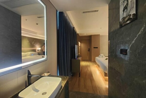 A modern bathroom with a large mirror, a rectangular sink, and a wooden floor.