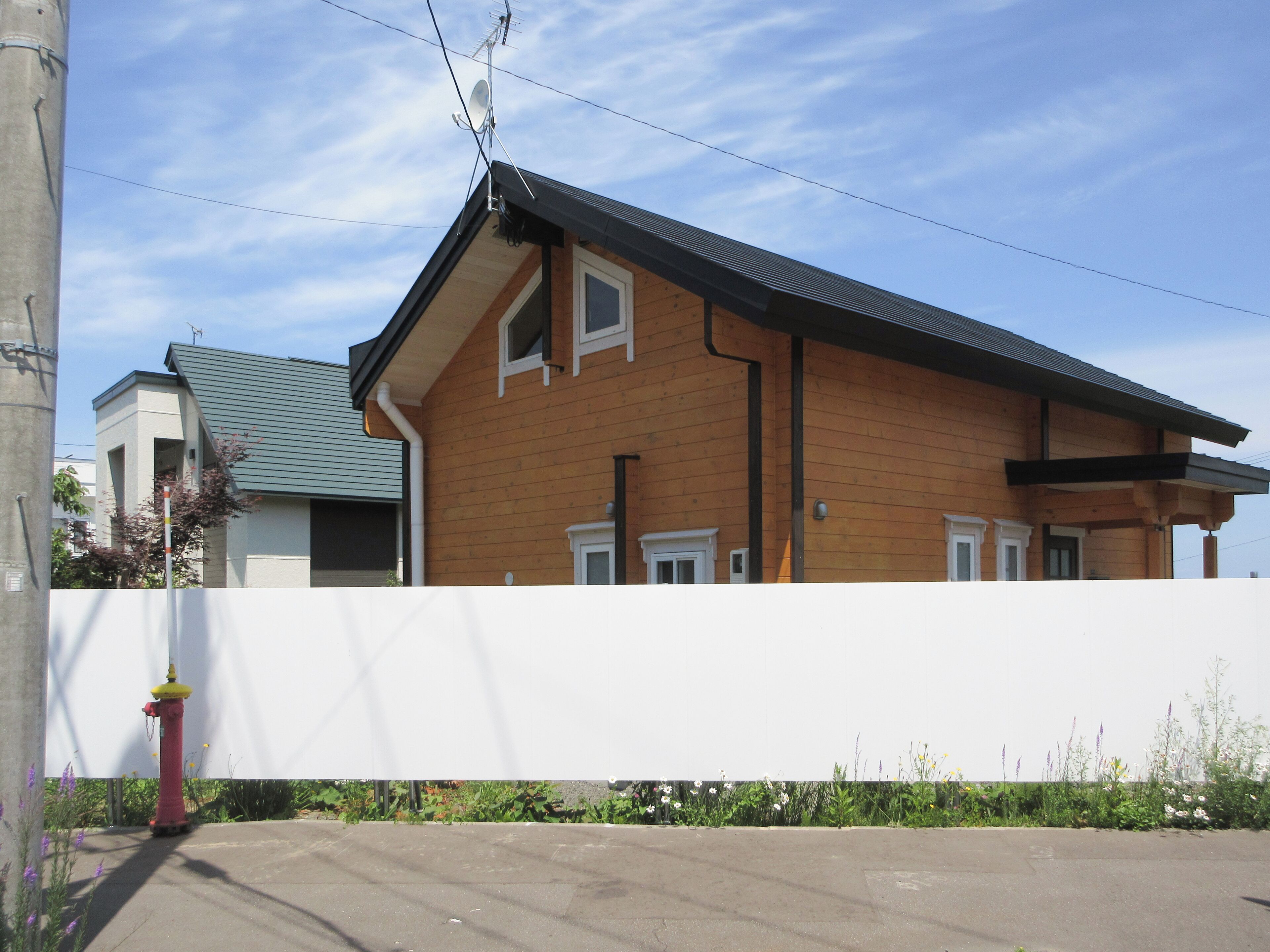 Una casa a due piani in legno con tetto spiovente, parabola e camino ben visibile.