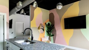 A kitchen with a granite countertop, a black faucet, and a modern pendant light.
