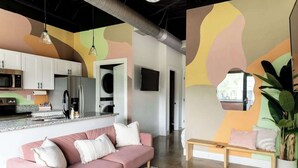 A modern living room with a pink sofa, a wooden coffee table, and a large mirror.