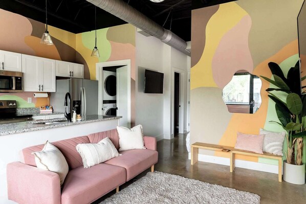 A modern living room with a pink sofa, a wooden coffee table, and a large mirror.