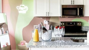 A kitchen with white cabinets, a microwave, and a granite countertop. There are glasses with strawberries and a bottle of champagne.