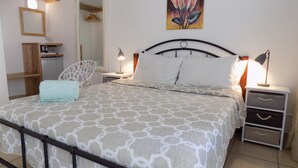 A bedroom with a bed, two bedside tables, a nightstand, a mirror, a wardrobe, and a painting on the wall. - Villa Osumare (Flic-en-Flac)
