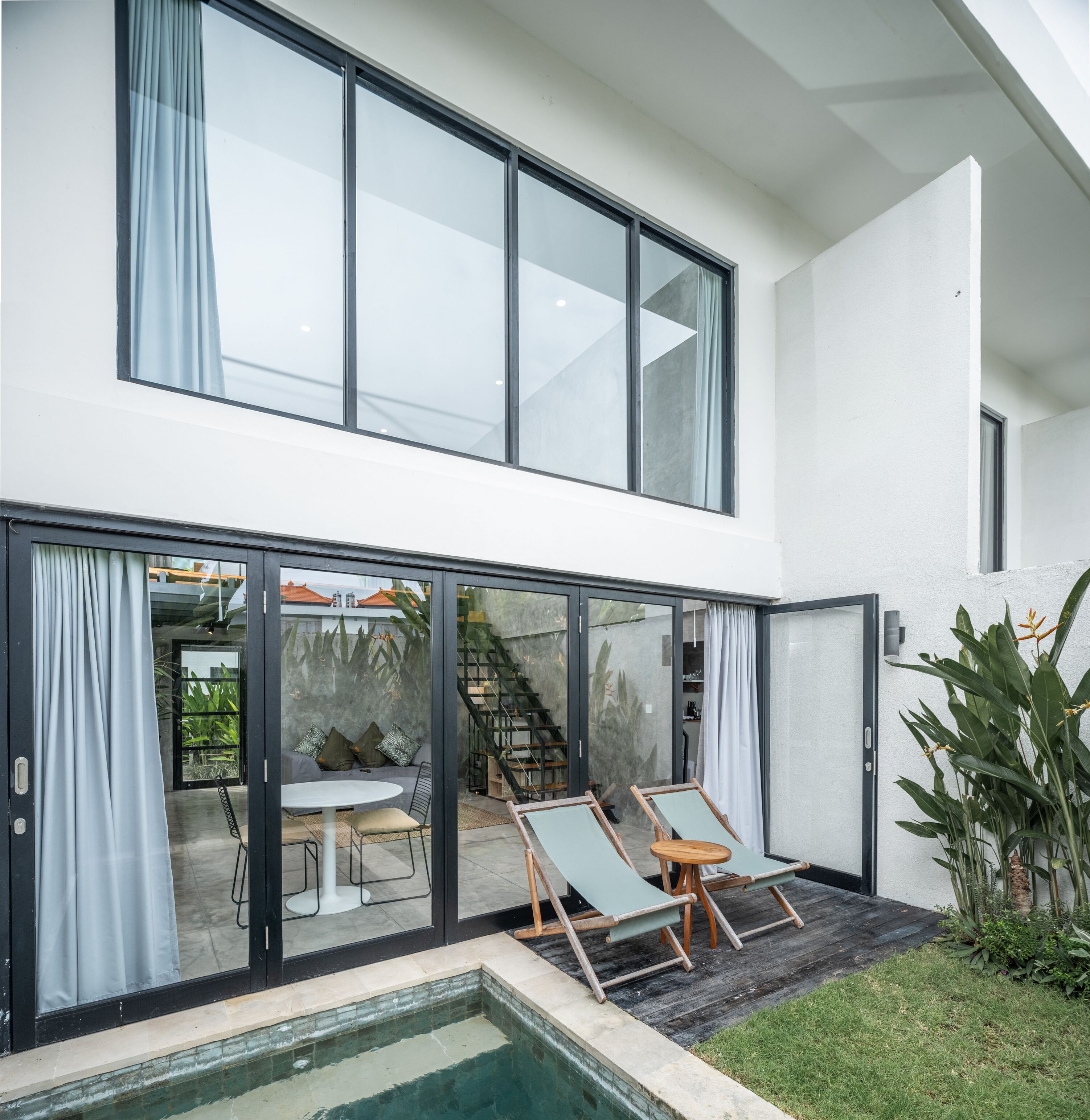 A modern two-story house with a glass door leading to a patio area.